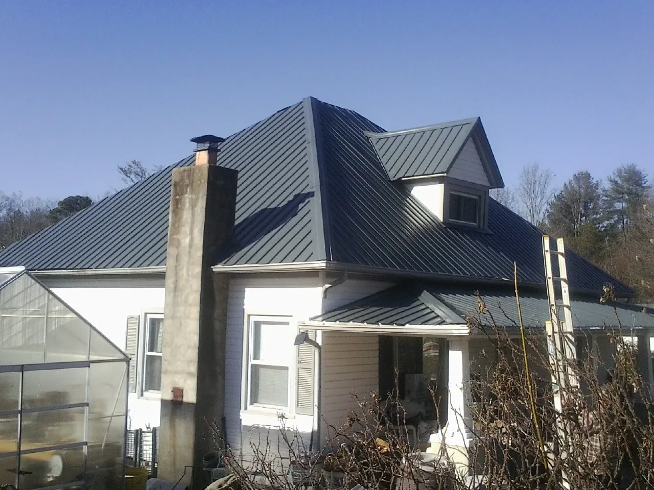 Dark blue standing seam metal roof on a white farmhouse with dormer — Slate & Tile Roof Repair by Roofing Brothers in Parlin
